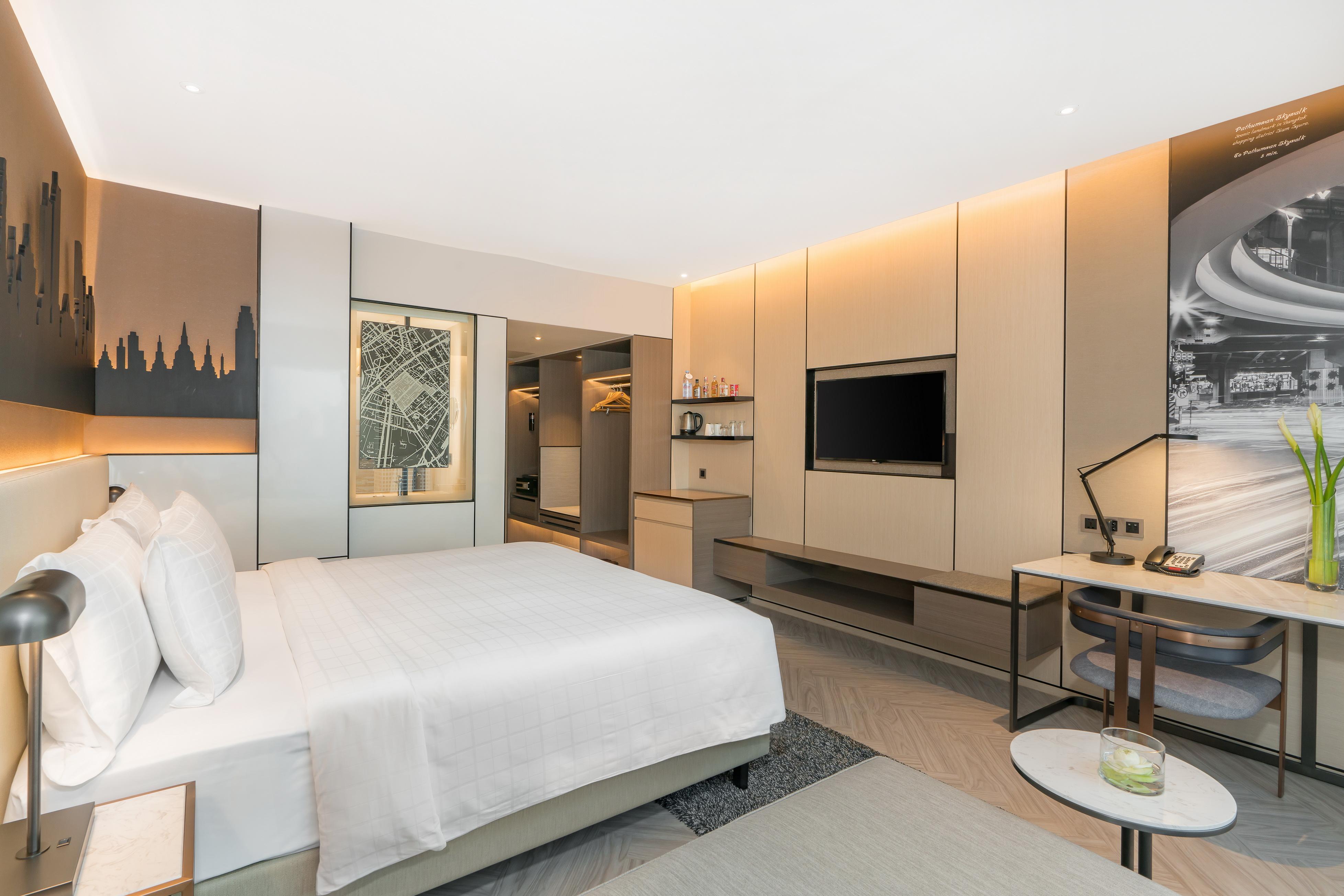 帕色哇公主酒店【SHA Extra Plus】 曼谷 外观 照片 The photo shows a modern hotel room with a contemporary design. It features a large bed with white linens and plush pillows. The room is well-lit with warm lighting, creating an inviting atmosphere. There is a wall-mounted flat-screen TV opposite the