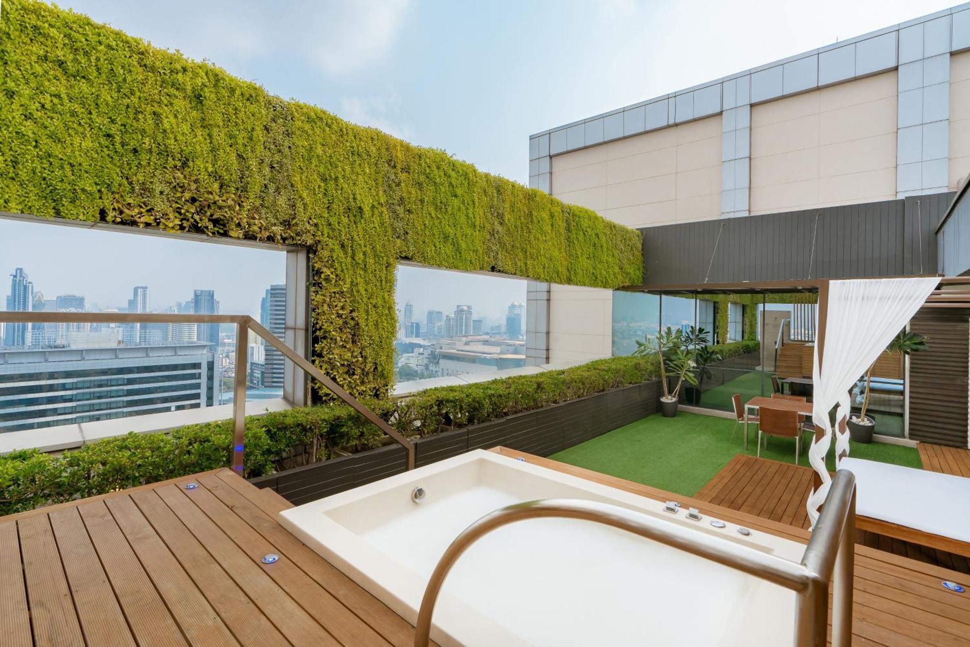 帕色哇公主酒店【SHA Extra Plus】 曼谷 客房 照片 The photo shows a rooftop terrace featuring modern design elements. There is a small, white hot tub positioned on a wooden deck, and surrounding it are green plants and a lush vertical garden that adds a touch of nature. The area is elegantly furnish